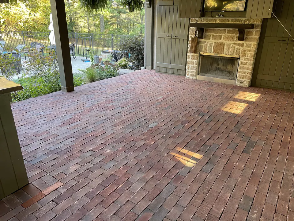 Brick paver floor laid in running bond under a covered porch with a stone fireplace