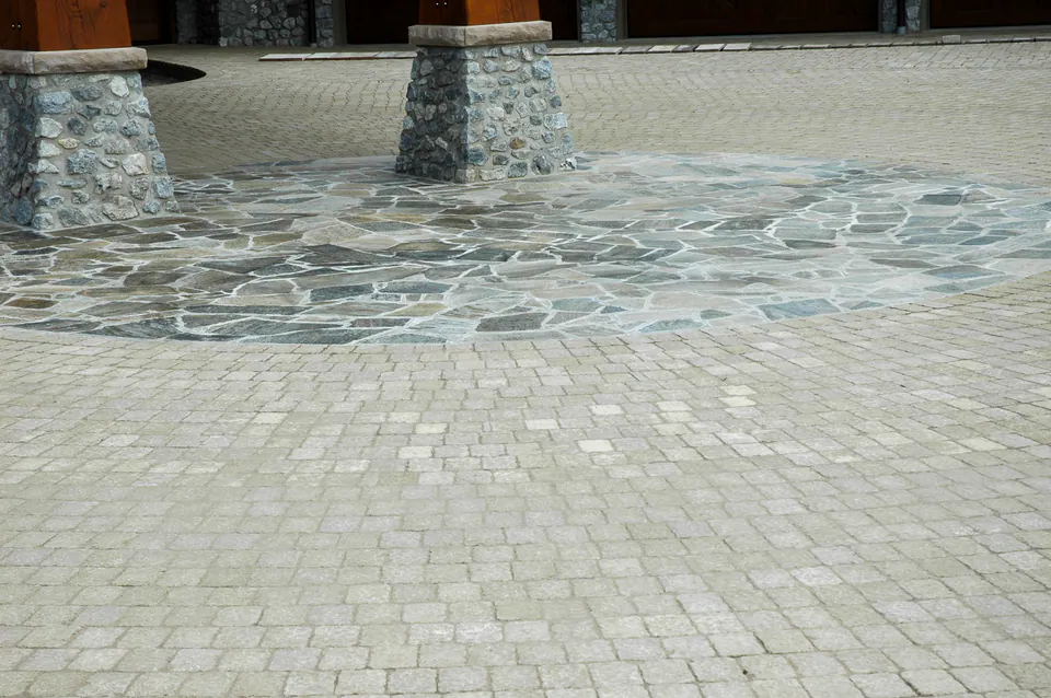 Close view of a concrete paver driveway field with paver border courses and natural stone column bases