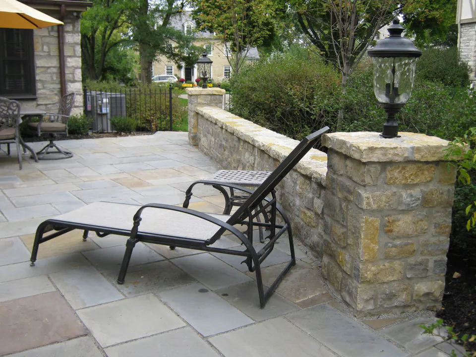 Flagstone patio with a limestone seat wall, pier lantern and lounge chair