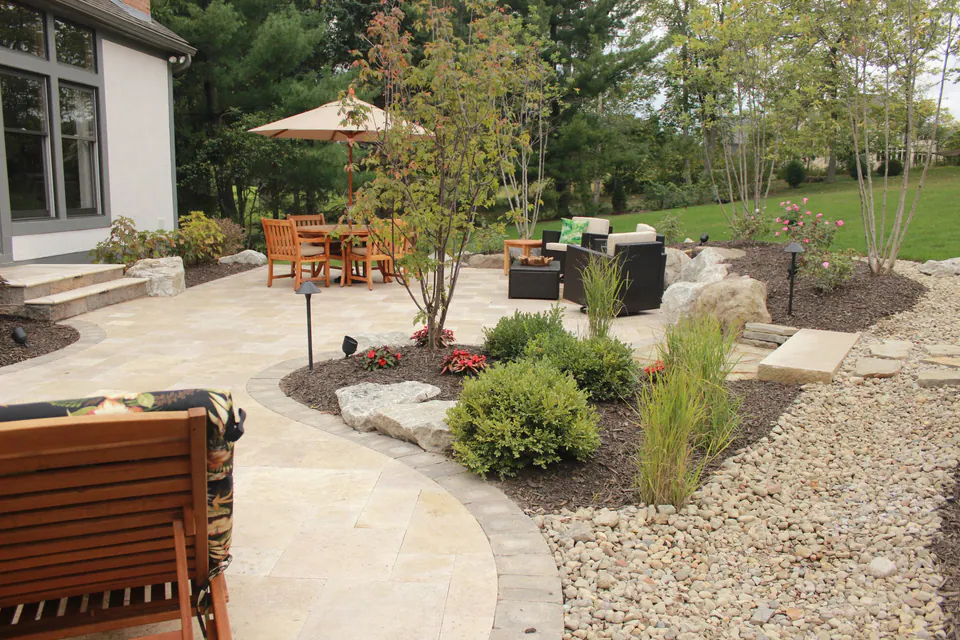 Natural stone patio with dining and lounge areas, curved edges and gravel planting beds