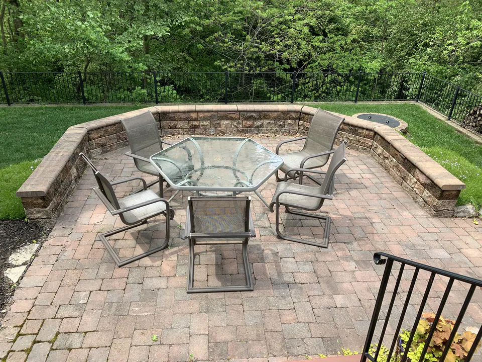 Paver patio with a curved block seat wall around a glass dining table