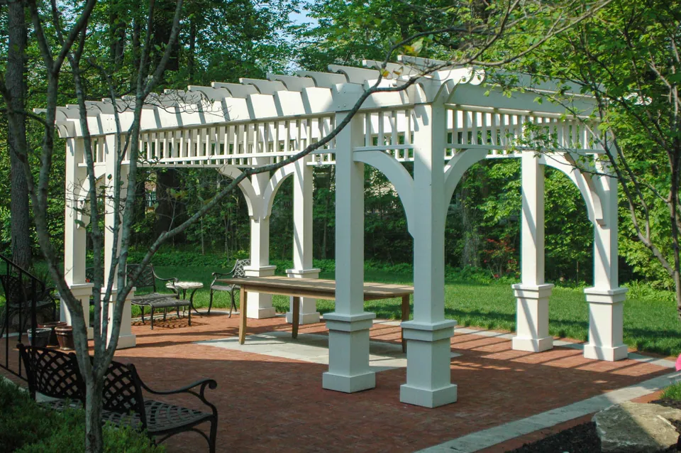 White garden pergola over a brick patio and seating area