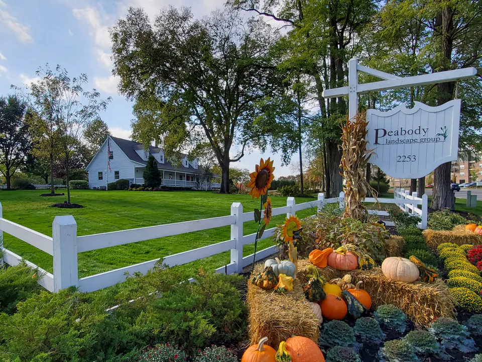 Wide view of the Peabody home office, lawn, fence, sign, and fall display