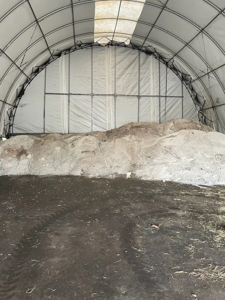 Large pile of bulk road salt stored under a fabric-covered dome